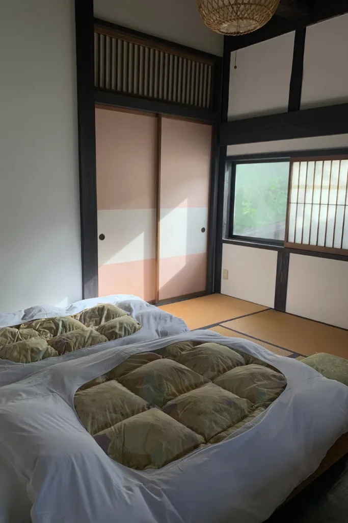 Habitación con futones, tatami y puertas shoji en ryokan para un viaje a Japón auténtico.