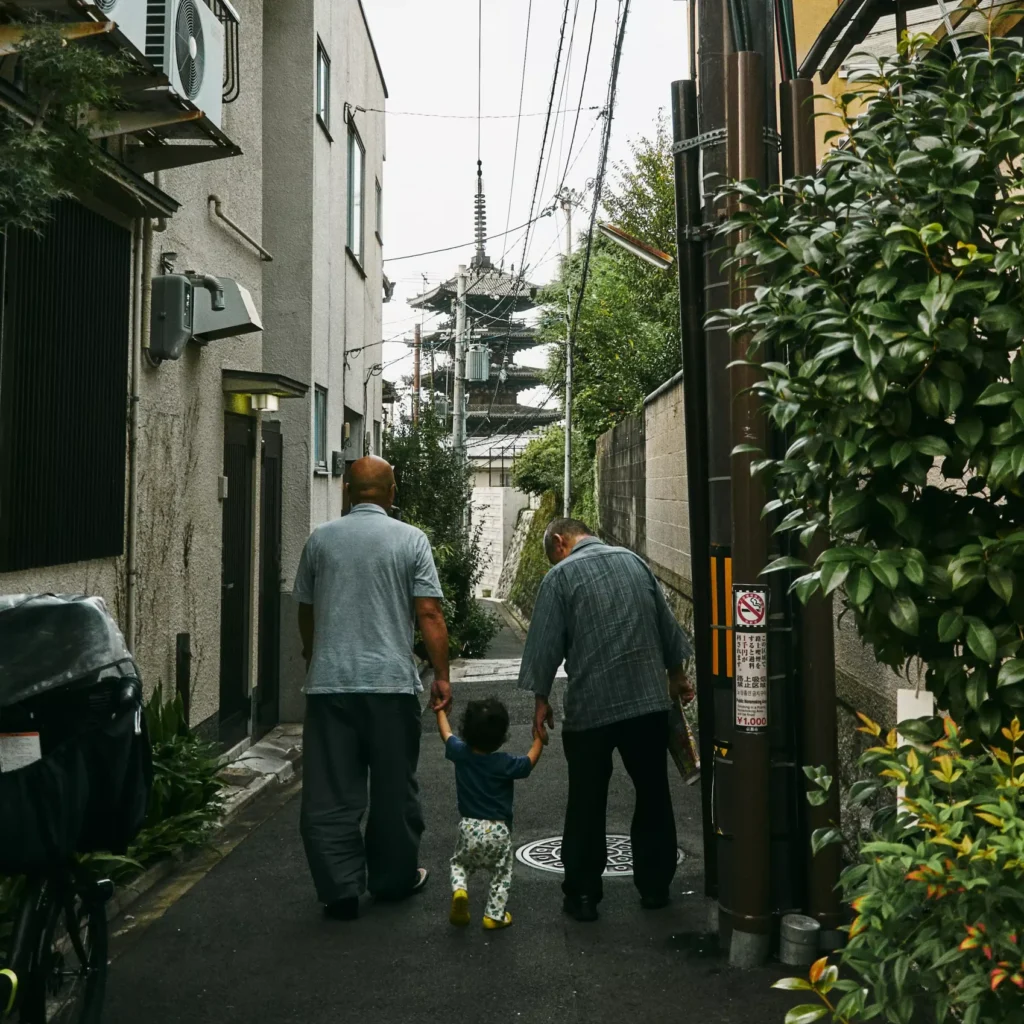 Dos personas mayores y un niño caminando hacia una pagoda en Japón