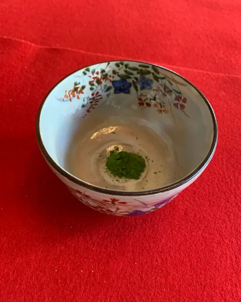 Chawan con matcha en polvo sobre tatami rojo