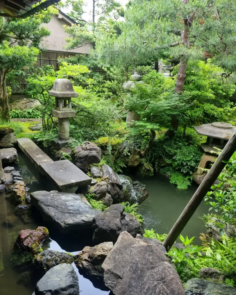 Jardín con estanque, rocas y linternas en la casa Nomura