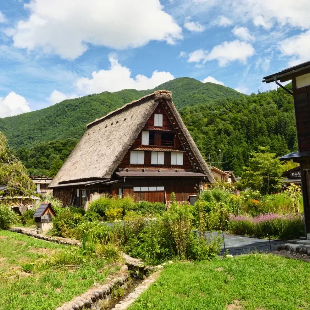 Casas gassho-zukuri de Shirakawago en los Alpes Japoneses, rodeadas de montañas y campos verdes.