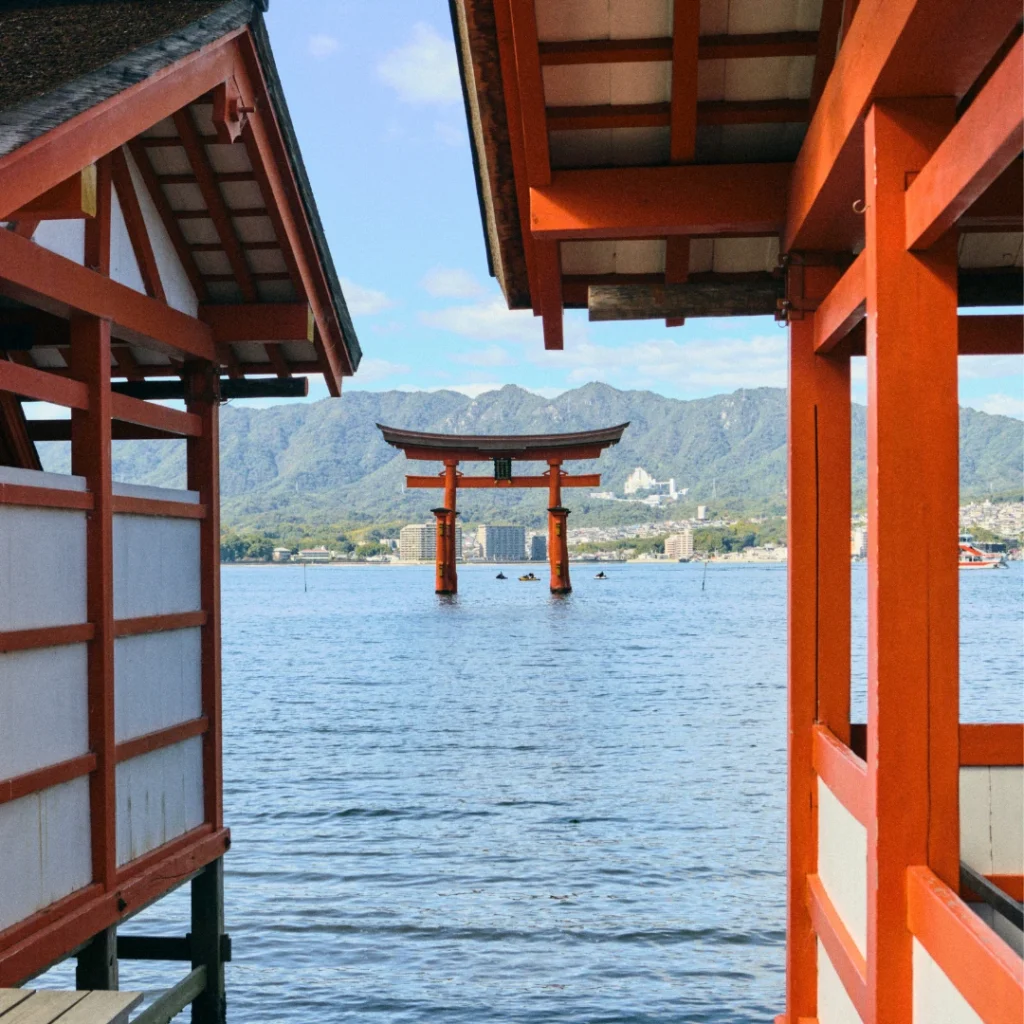 Torii flotante de Itsukushima en Miyajima en medio del mar con montañas al fondo.