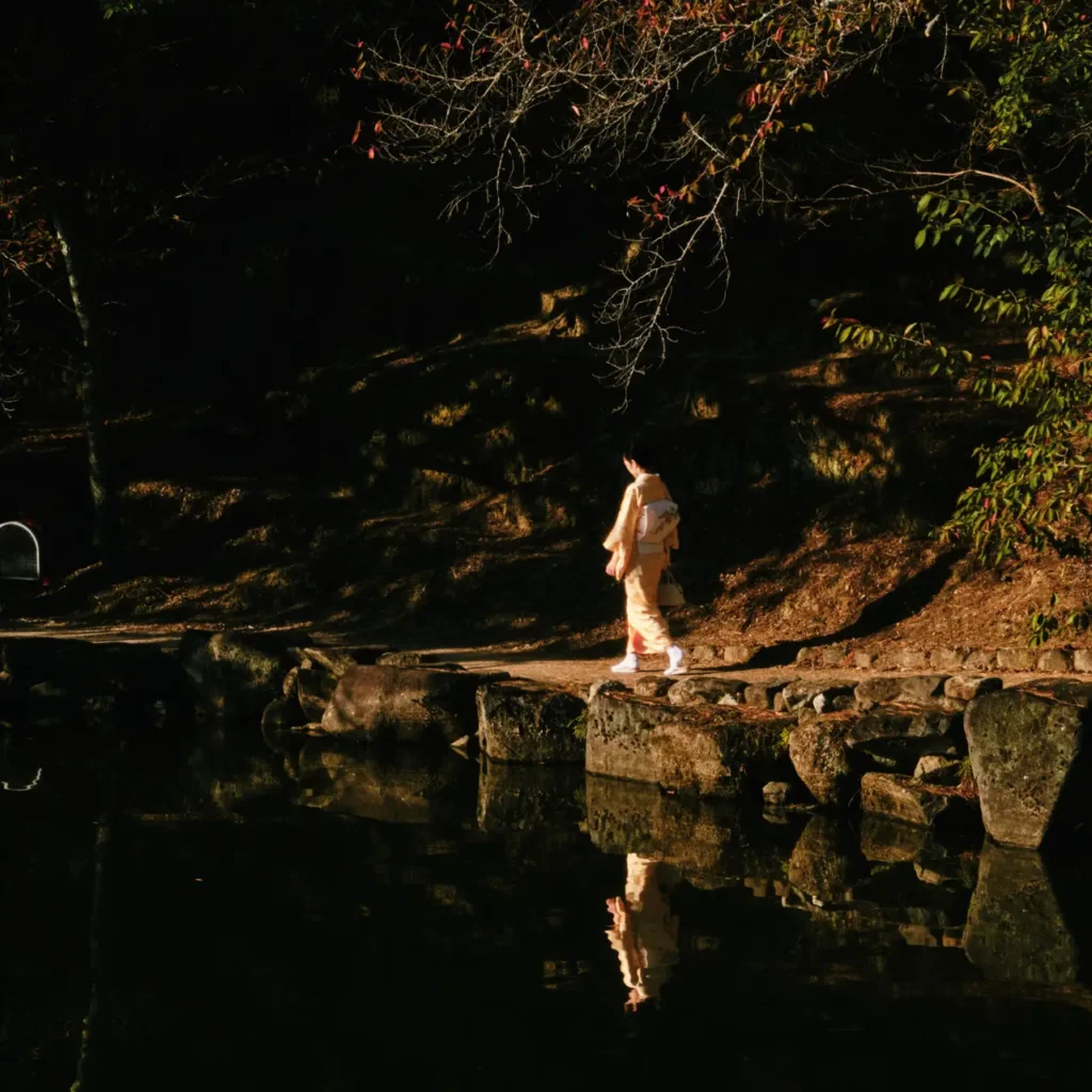 Persona con kimono caminando junto a un estanque durante el otoño en Japón