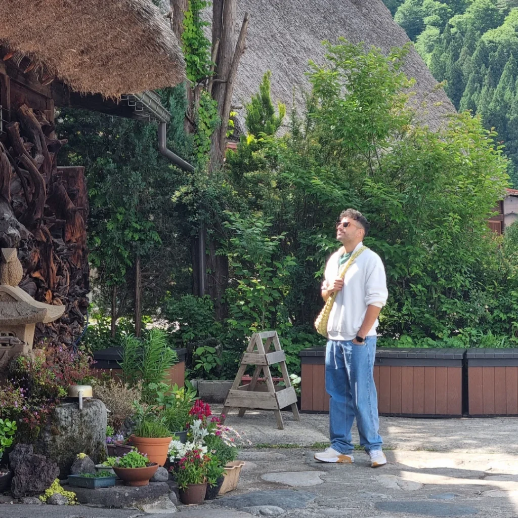 Persona caminando entre casas gassho-zukuri rodeadas de vegetación en Shirakawago.