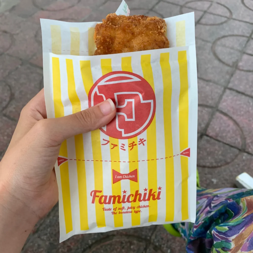 Mano sujetando un famichiki de pollo crujiente, snack rápido y no picante que suele gustar a niños en Japón.