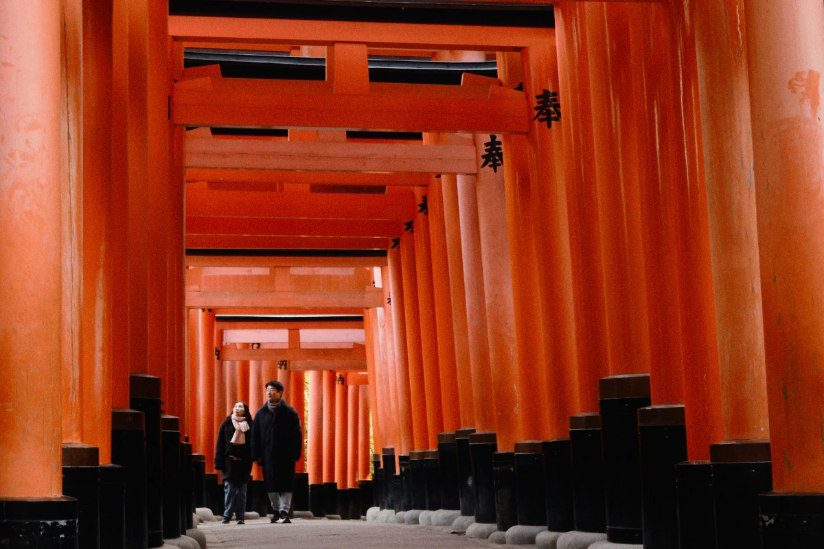 Pareja caminando entre torii rojos en Fushimi Inari durante su luna de miel