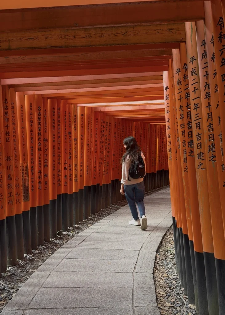 Guía local caminando entre los torii de Fushimi Inari en un santuario de Japón