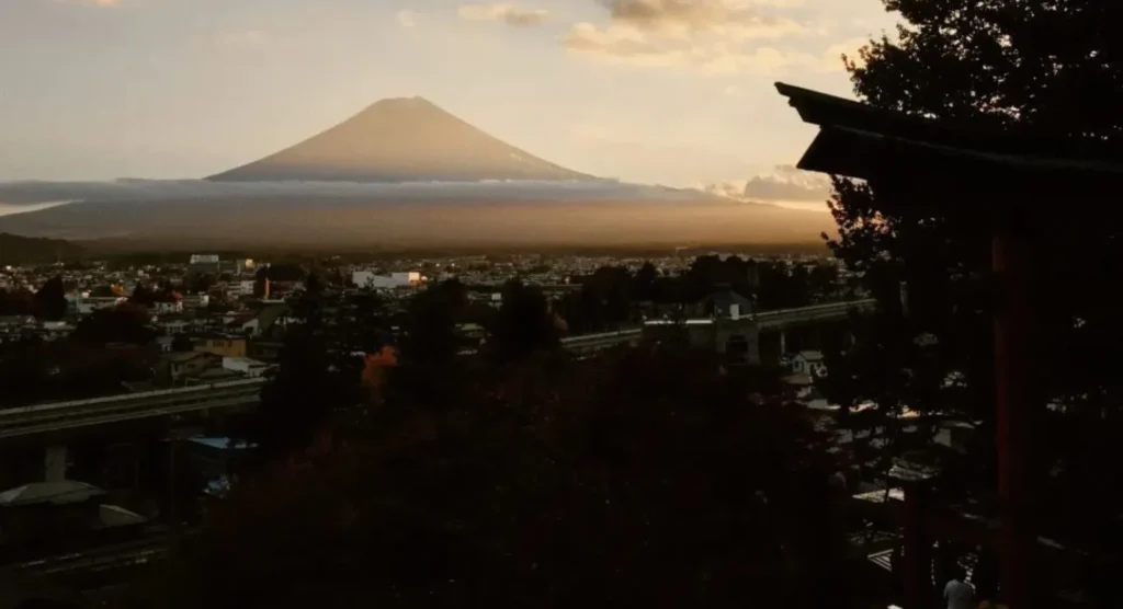 Monte Fuji al atardecer con una ciudad a sus pies y la pagoda chureito en primer plano a la derecha.