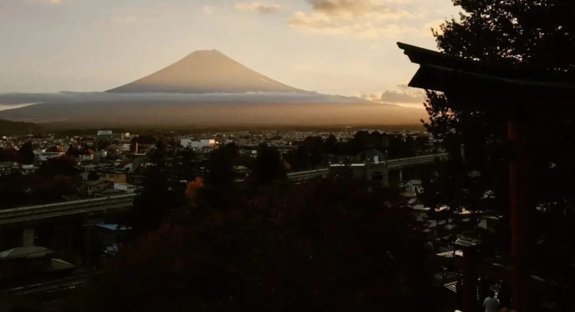 Monte Fuji al atardecer con una ciudad a sus pies y la pagoda chureito en primer plano a la derecha.